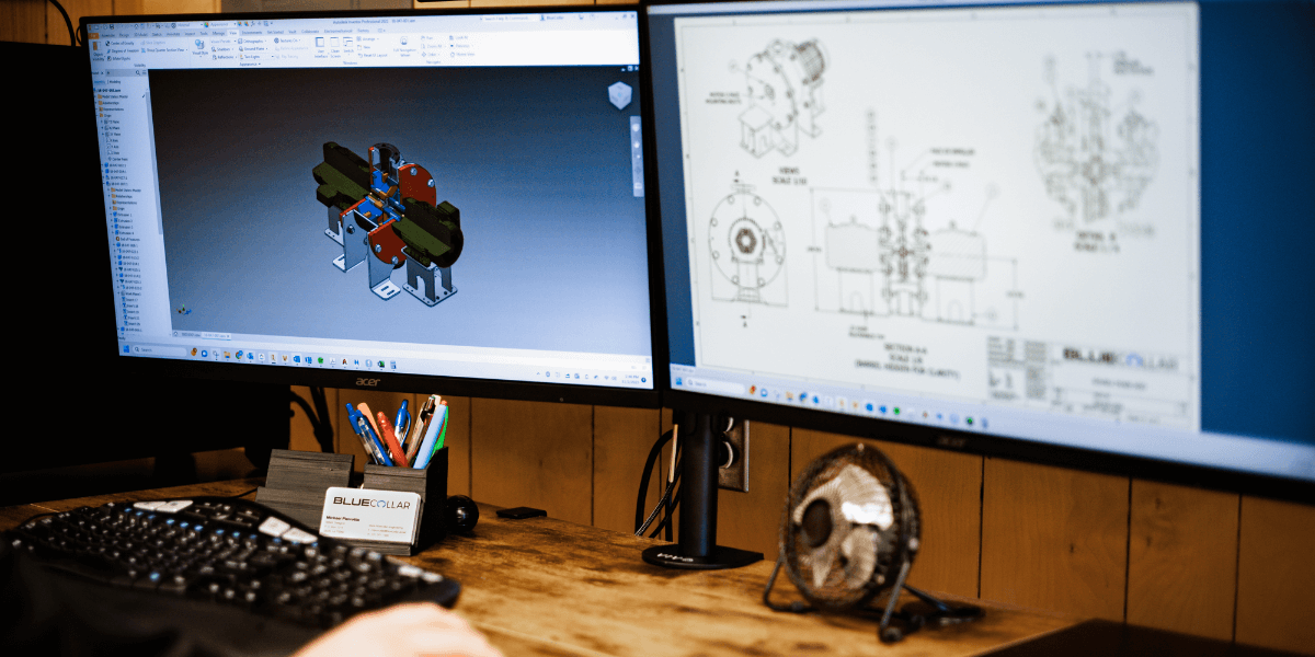 An designer from Blue Collar Engineering using CAD software on a computer with multiple monitors